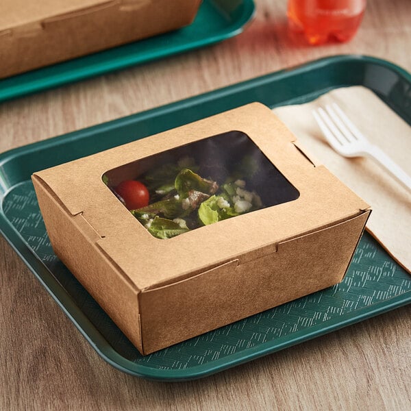 A salad in a Choice kraft paper take-out box with a window on a table.