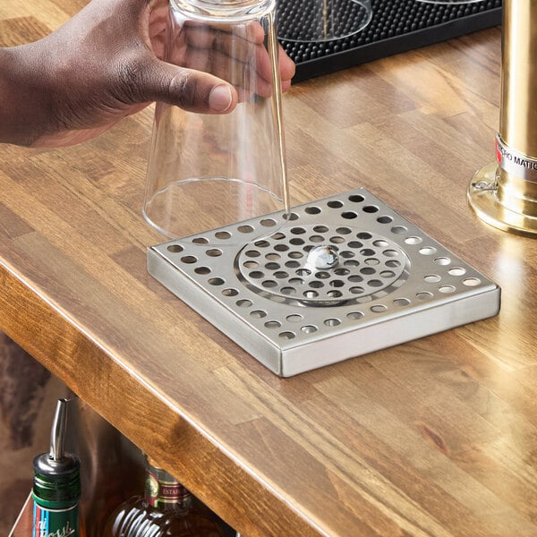 A stainless steel surface mount beer drip tray with a built-in glass rinser on a wooden countertop.
