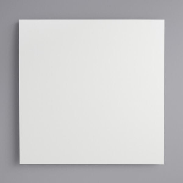 A white square melamine-coated wood cake board with feet.