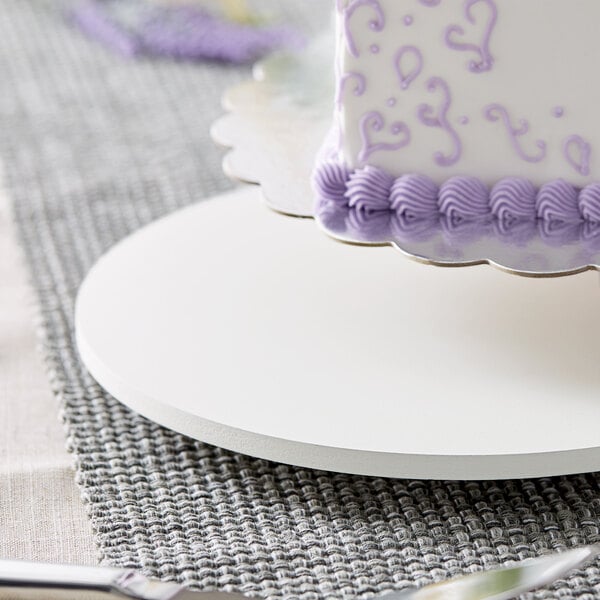 A white circular wood cake board with a cake on it.