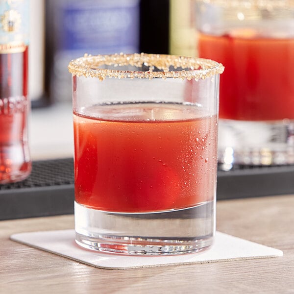 A Pasabahce old fashioned glass filled with a brown cocktail garnished with red and white.