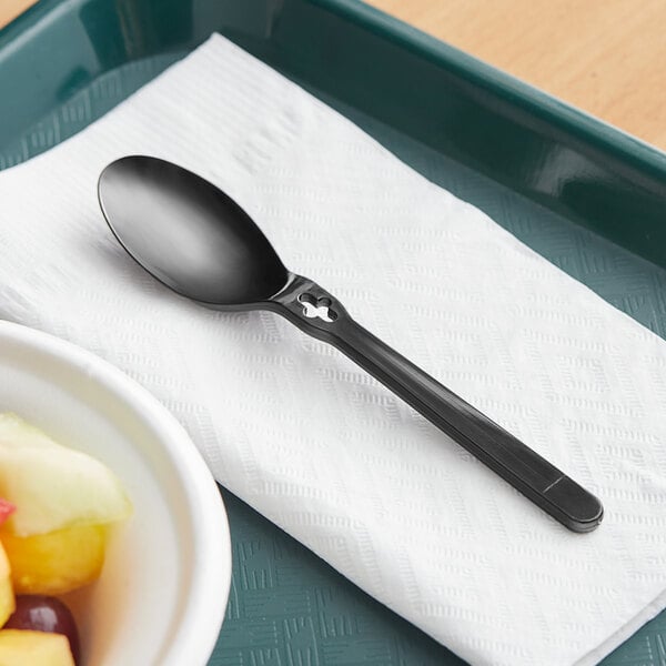 a spoon on a napkin and a bowl of fruit