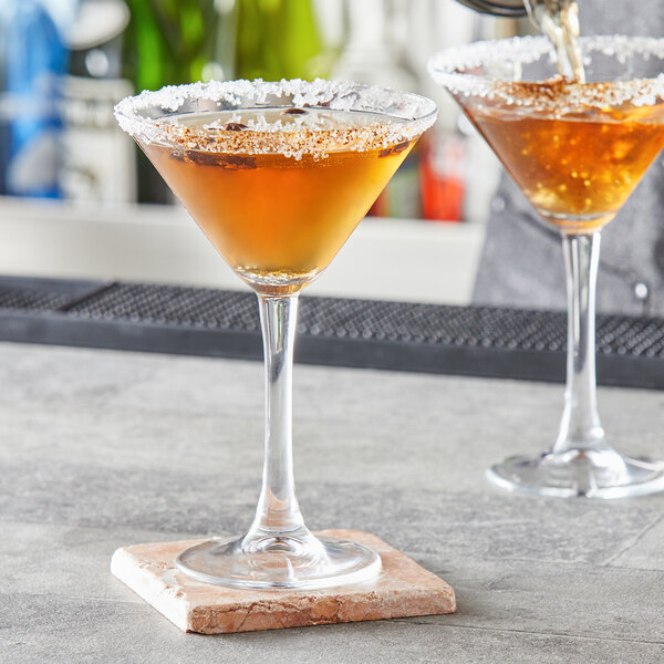 A person pouring two martinis into Pasabahce Imperial Plus martini glasses.