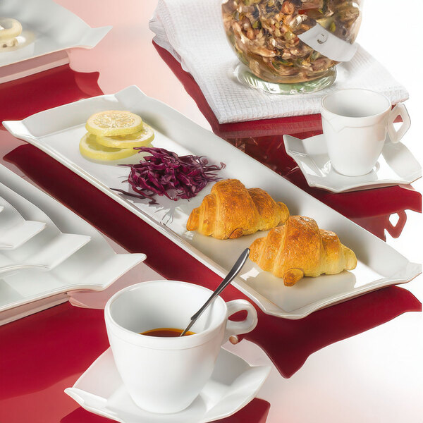 A CAC rectangular china platter with food and coffee on a table.