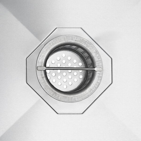 A Regency stainless steel floor mounted mop sink with a metal drain with holes in it.