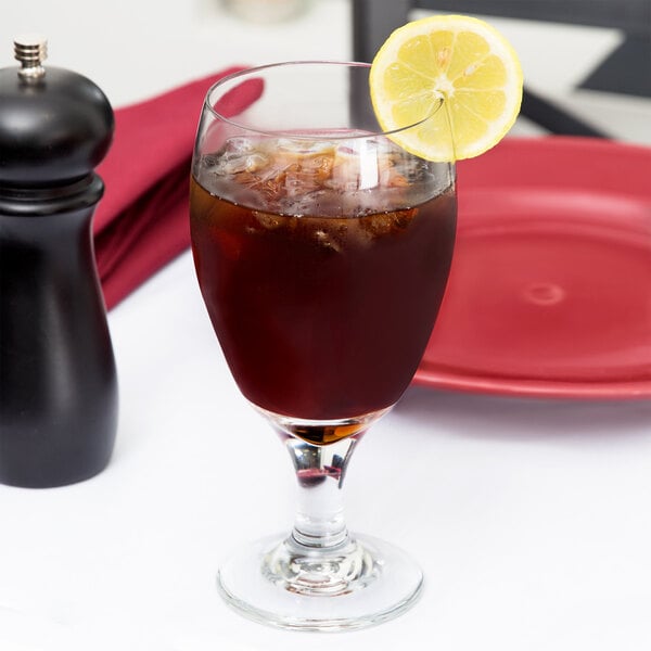 A Libbey tall iced tea glass filled with brown liquid, ice, and a lemon slice.