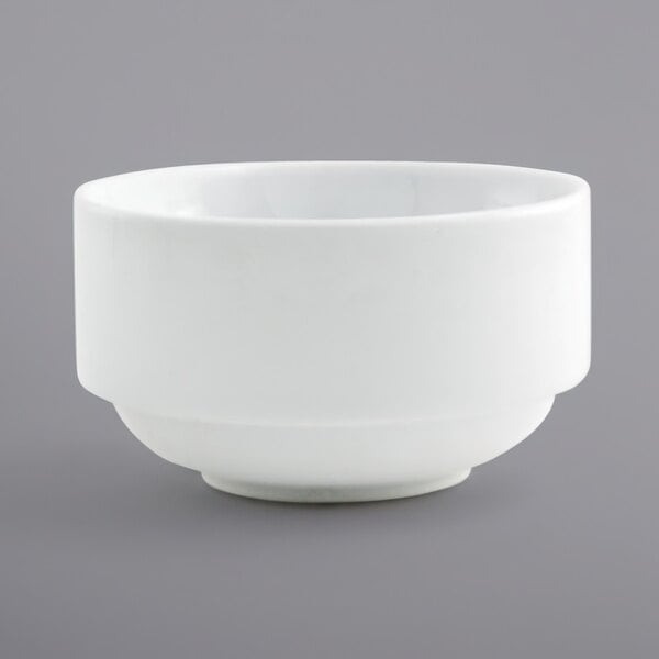 A stackable white porcelain bowl with a small rim on a gray surface.
