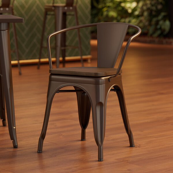 A Lancaster Table & Seating metal arm chair with a walnut wood seat and back.