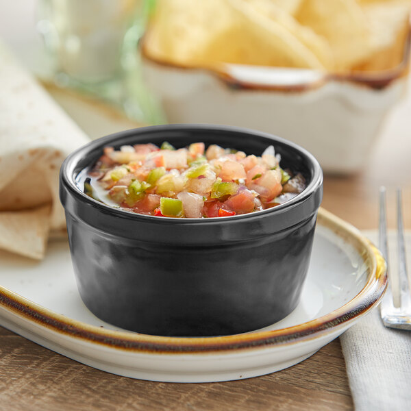 An Acopa Keystone stoneware ramekin filled with salsa and tortilla chips on a table.