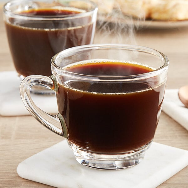 Two Acopa coffee cups on a table filled with coffee.