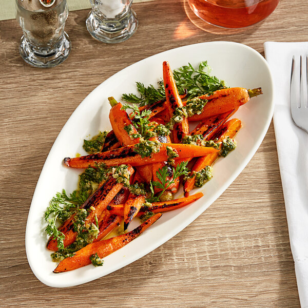 An Acopa Nova cream white triangle stoneware plate with food and carrots on it.