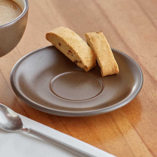 A plate with a cup of coffee on it and a saucer with a biscuit.