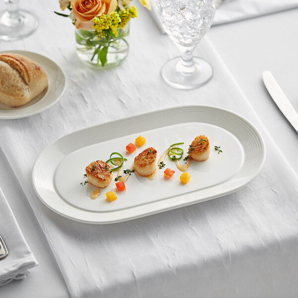 A white Acopa Liana porcelain platter with scallops and vegetables on it.