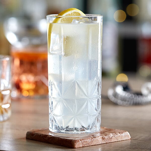A close-up of an Acopa Gardenia highball glass of water with a lemon slice.