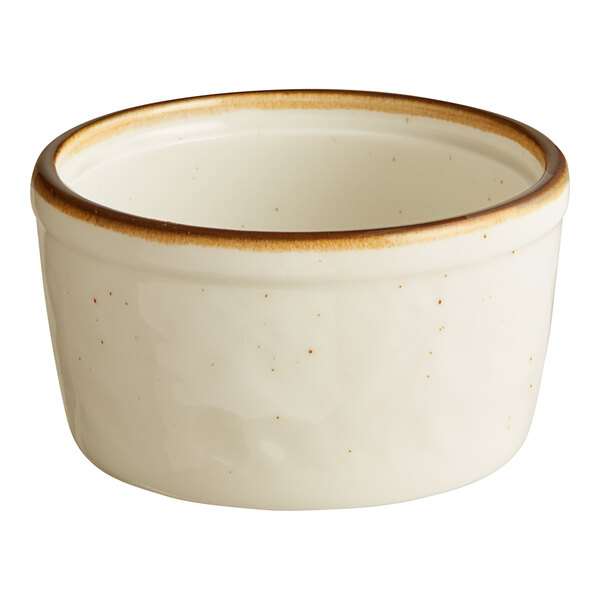 A small, round, cream-colored stoneware ramekin with a brown rim.