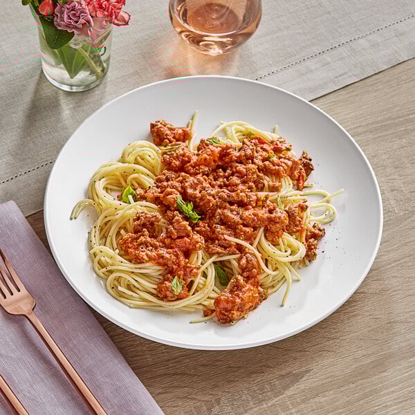 A plate of spaghetti with meat sauce on an Acopa matte white coupe plate with a fork.