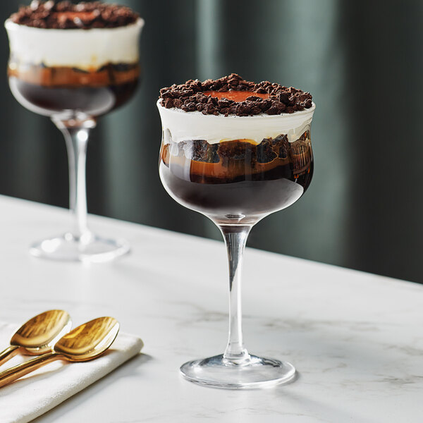 Two Acopa Deco cocktail glasses filled with chocolate and vanilla ice cream on a table.