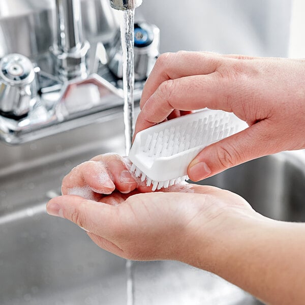 A person washing their hands with a Carlisle Sparta hand and nail brush.