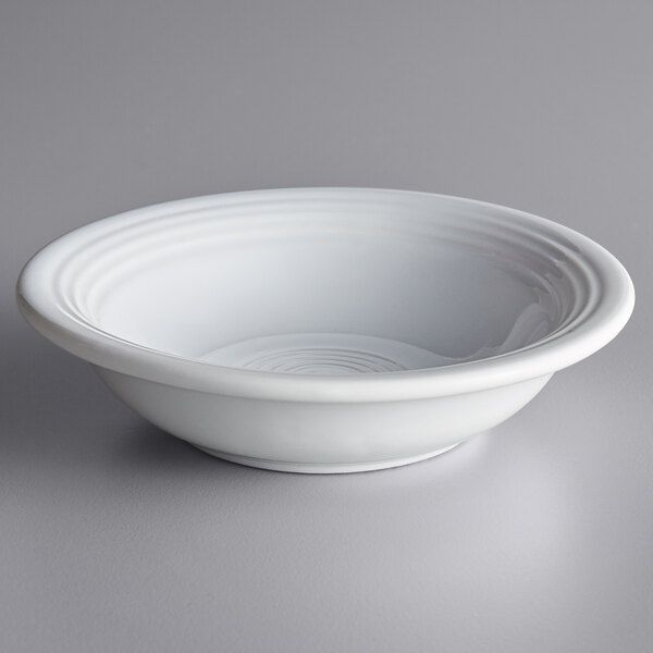 An Acopa Capri coconut white stoneware fruit bowl on a gray surface.