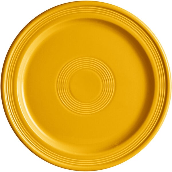 A close-up of a mango orange Acopa Capri stoneware plate with a circular pattern.