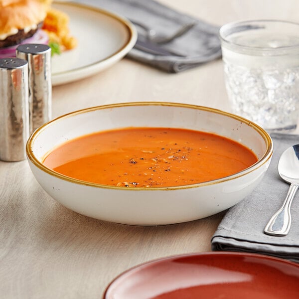 An Acopa Keystone Vanilla Bean stoneware low bowl filled with soup on a table.