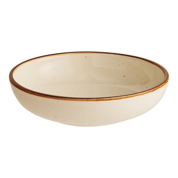 A cream-colored stoneware coupe low bowl with a brown rim.