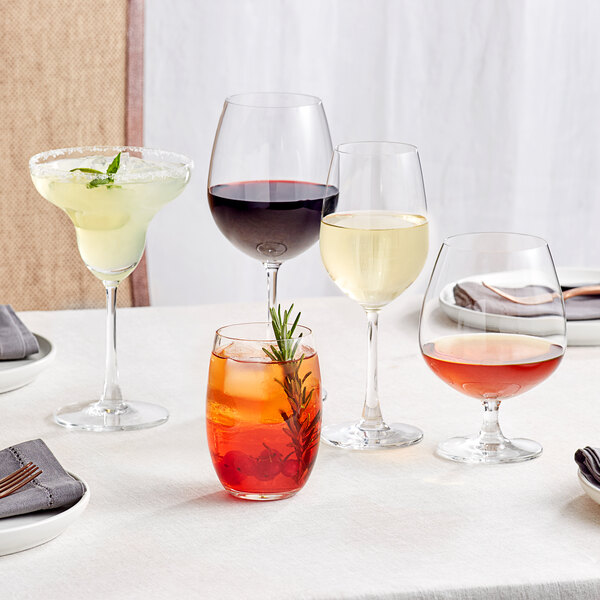 Acopa Covella Bordeaux wine glass on a table with a drink and a sprig of rosemary.