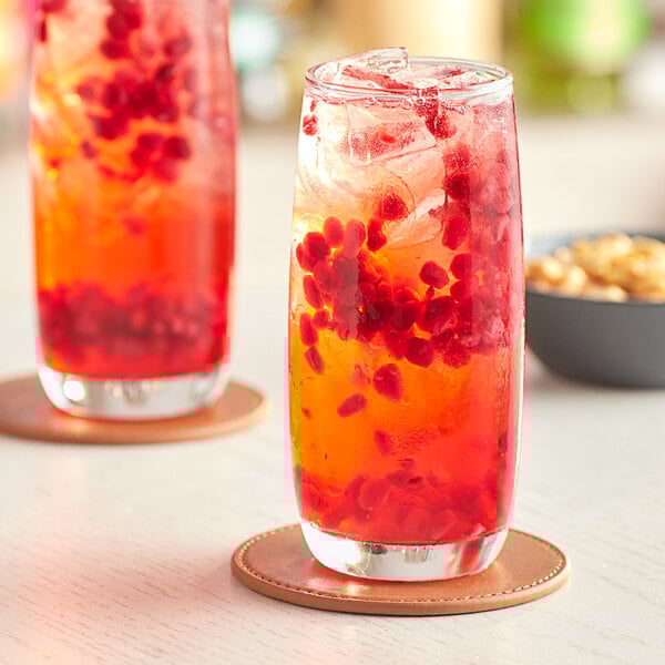 A close up of two Acopa beverage glasses with red and orange drinks and berries.