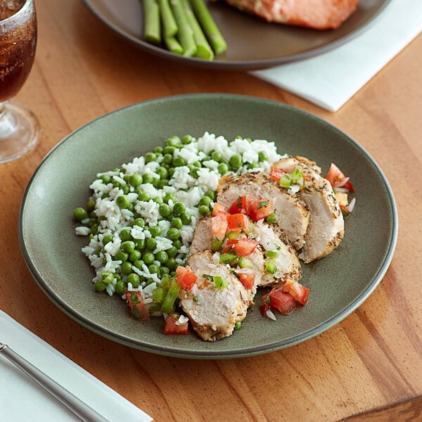 An Acopa Embers moss green matte coupe stoneware plate with rice, peas, and meat.