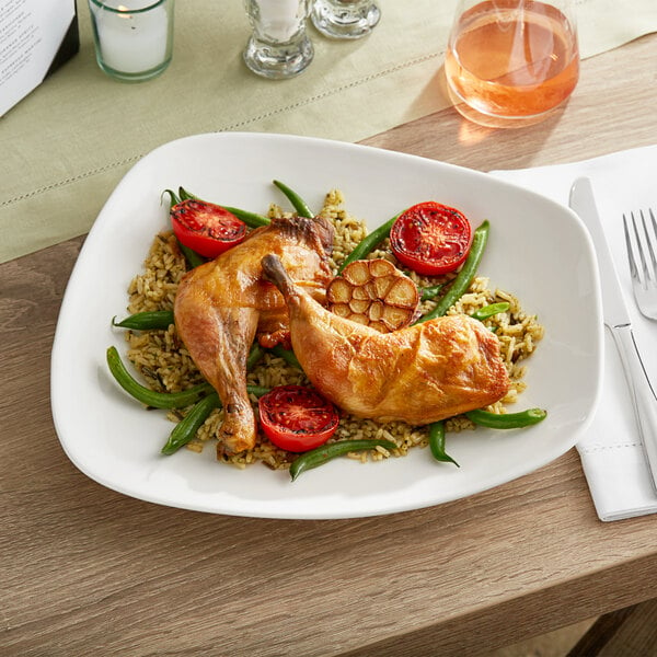 An Acopa Nova cream white stoneware plate with chicken and rice on it on a table.