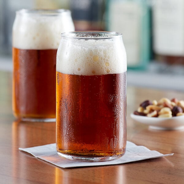 Two Acopa Select can glasses of beer on a table.
