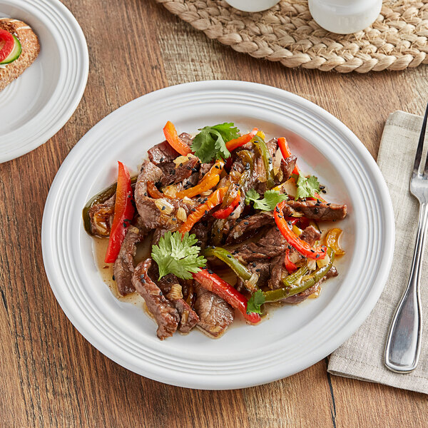 A Acopa Capri Coconut White stoneware plate with a meal of meat and peppers on it.