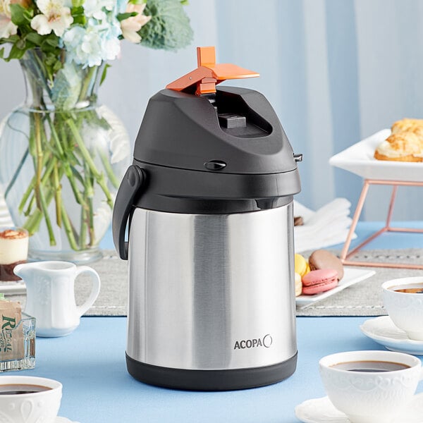 An Acopa stainless steel coffee airpot with decaf label on a table.