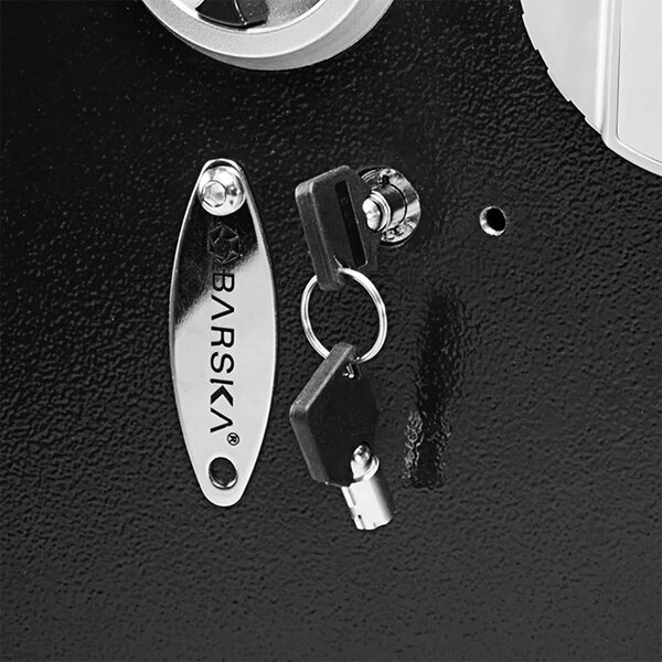 The right side of a black Barska wall safe door with a key in the lock.