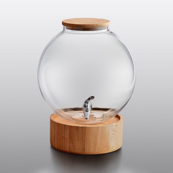 An Acopa glass beverage dispenser with a cork lid and wood base.