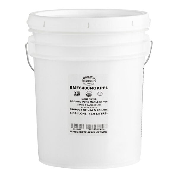 A large white plastic bucket with a metal handle and a label indicating it contains 5 gallons (18.9 liters) of organic pure maple syrup.