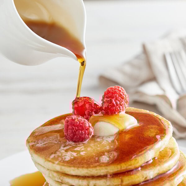 A stack of pancakes with Butternut Mountain Farm Organic Vermont Maple Syrup and raspberries.