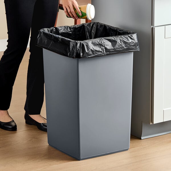 A gray square 25-gallon trash can with a black liner.