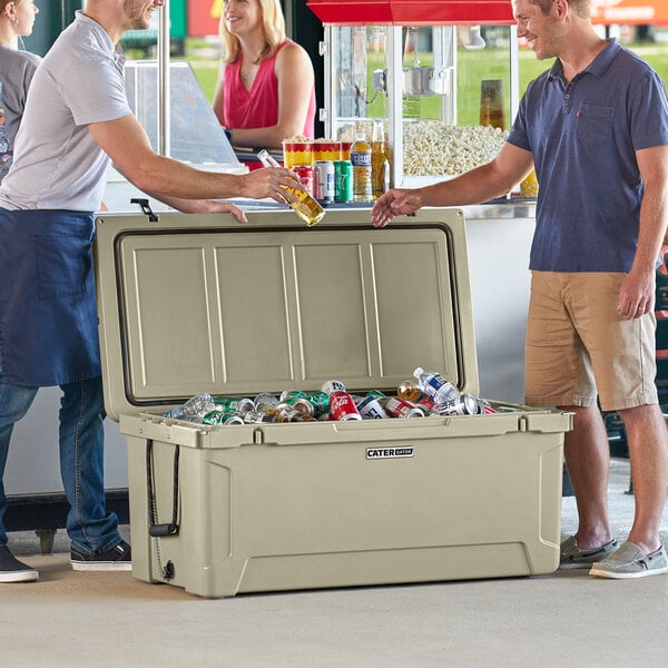 Two men selecting drinks from a large, open cooler filled with various beverages.