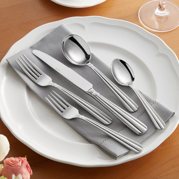 A white plate with Acopa Harmony stainless steel flatware on it.