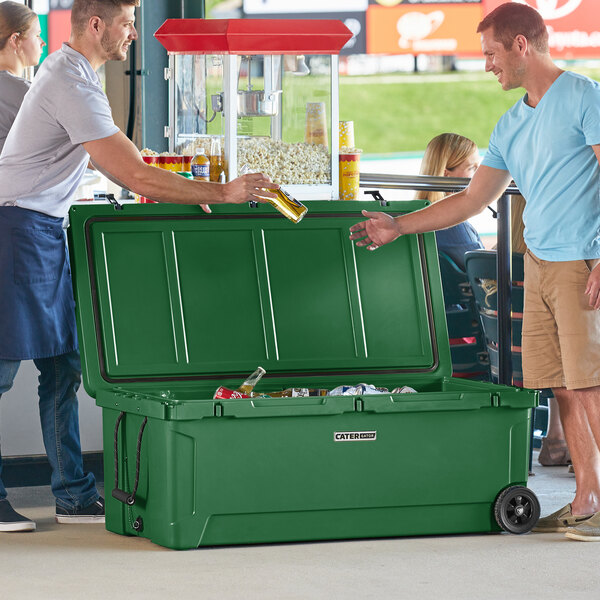Two men standing next to a green CaterGator outdoor cooler.