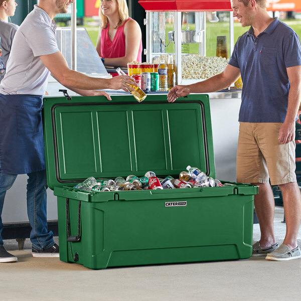 Two men standing next to a CaterGator hunter green cooler with a large green lid full of cans.