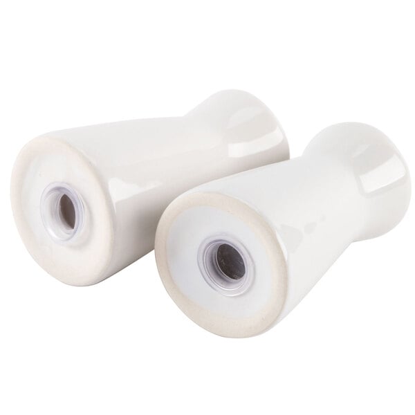 A close-up of two white ceramic tower salt and pepper shakers.