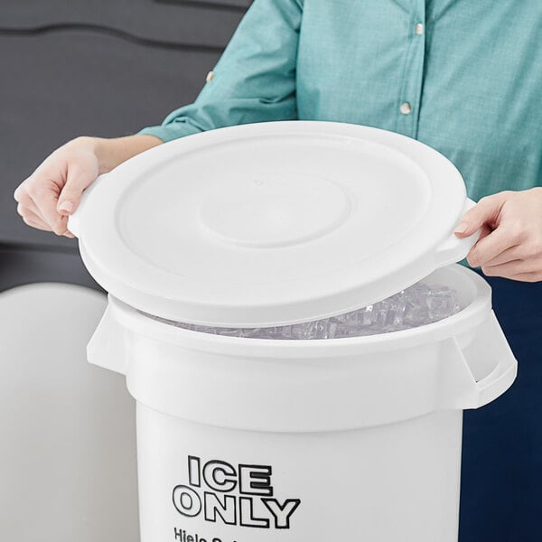 A person holding a white lid on a white bucket filled with ice.