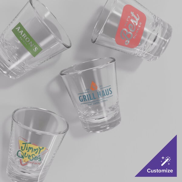 A stack of clear Choice SAN plastic shot glasses with red custom labels.