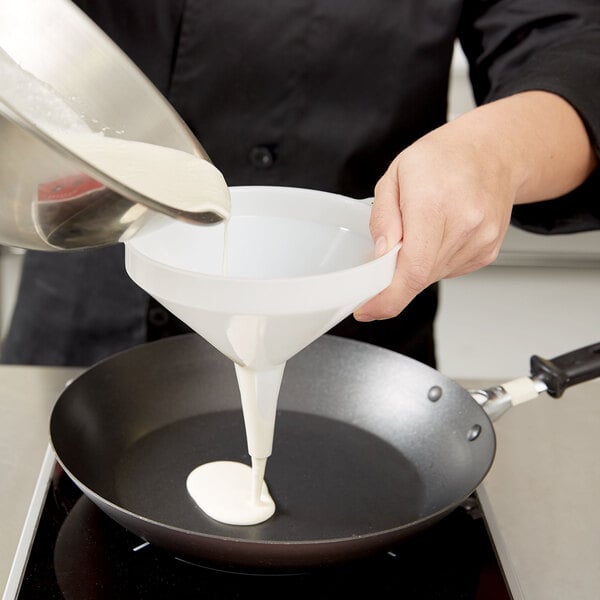 A person pouring white liquid into a funnel.