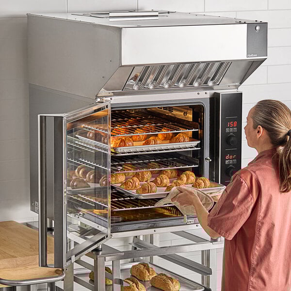 A woman putting food into a Moffat Turbofan convection oven.