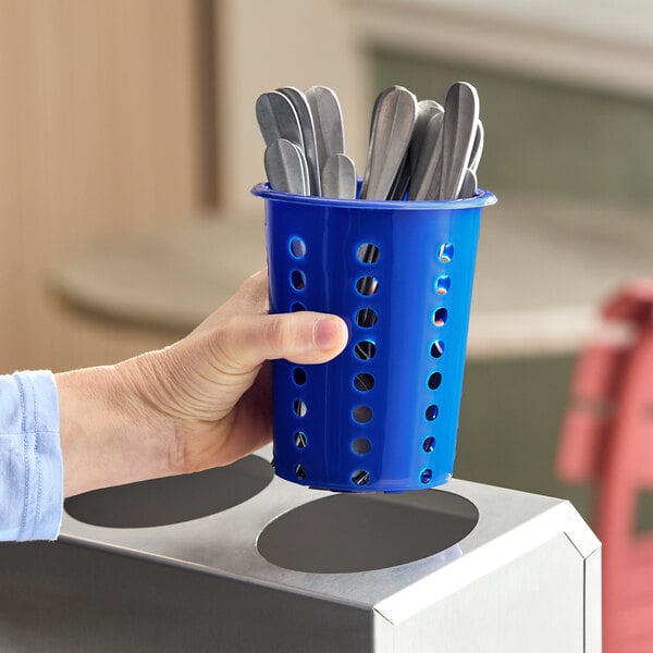 A blue perforated plastic flatware holder cylinder containing metal utensils.