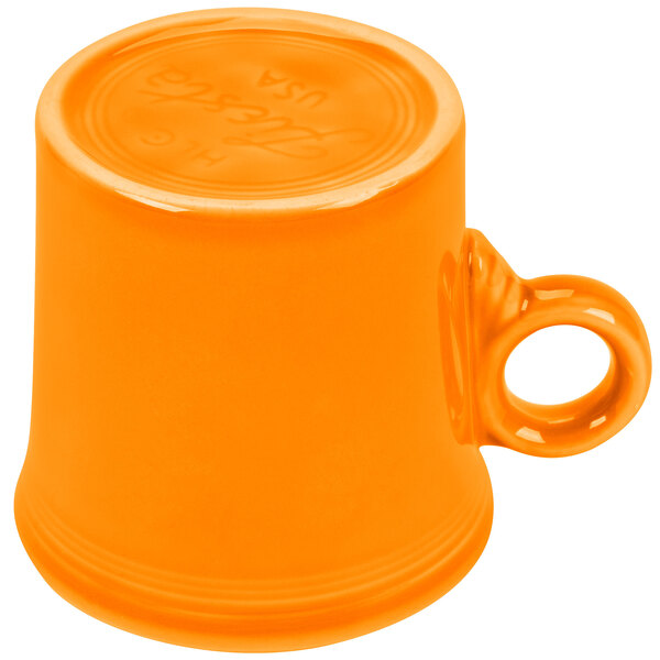 A small orange Fiesta mug with a handle.