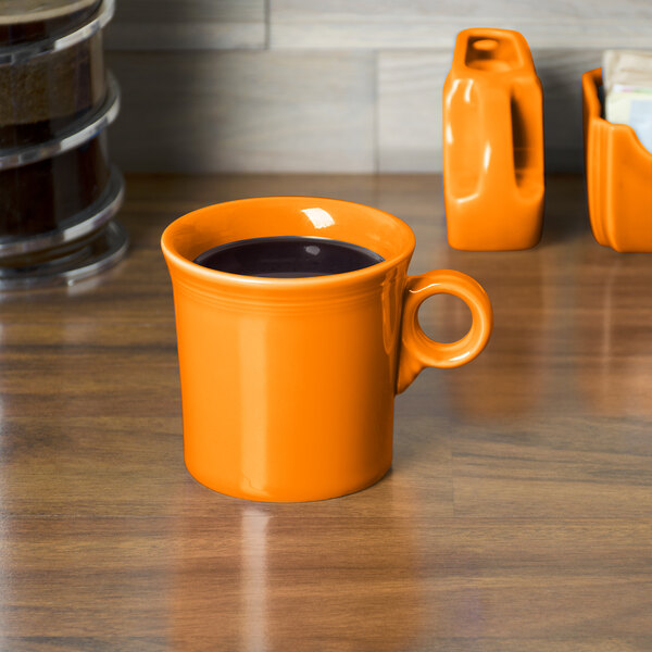 A Tangerine Fiesta china mug filled with coffee on a table.